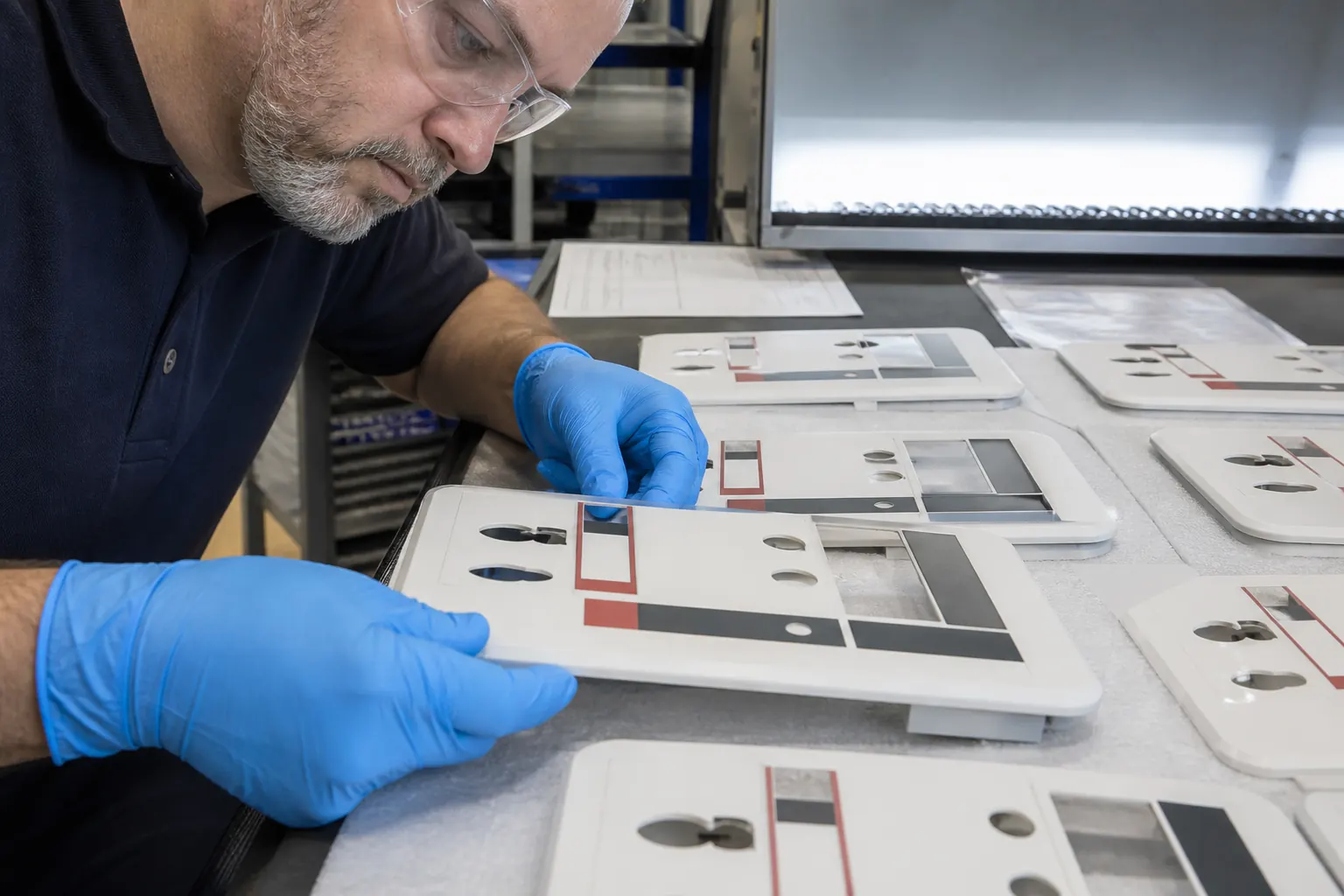 Asian factory technician inspecting a batch of printed flat textured plastic housings